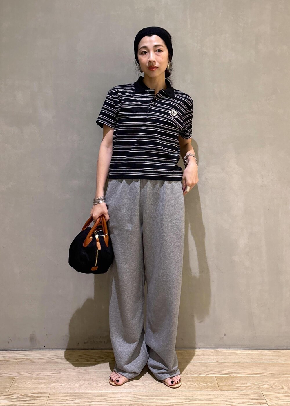 グレー系のスウェットパンツ、ブラック系のポロシャツを着用したレディースの夏コーディネートの3枚目の写真