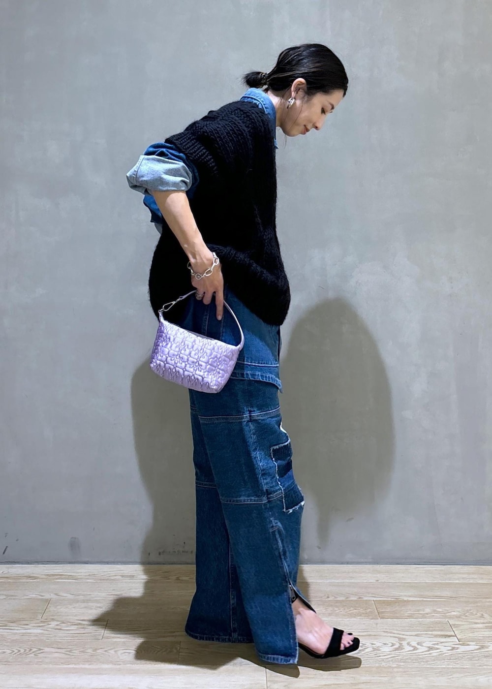 パープル系のハンドバッグ、ブルー系のカバーオール、ブルー系のデニムパンツを着用したレディースの夏コーディネートの3枚目の写真