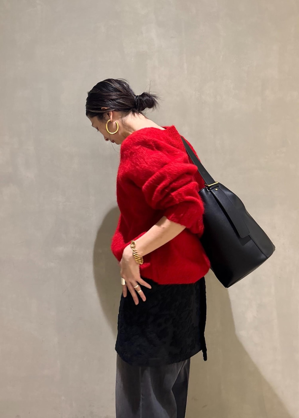 レッド系のニット/セーター、ブラック系のスカート、ブラック系のデニムパンツを着用したレディースの冬コーディネートの10枚目の写真