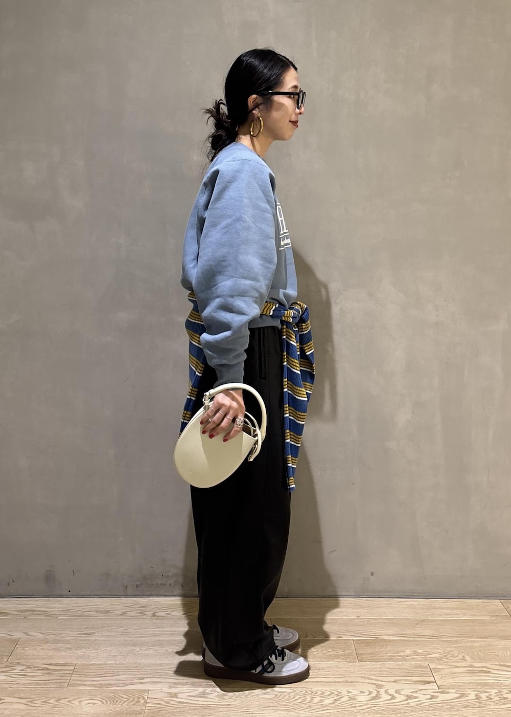 ホワイト系のハンドバッグ、ブルー系のスウェット、ブルー系のポロシャツを着用したレディースの秋コーディネートの3枚目の写真