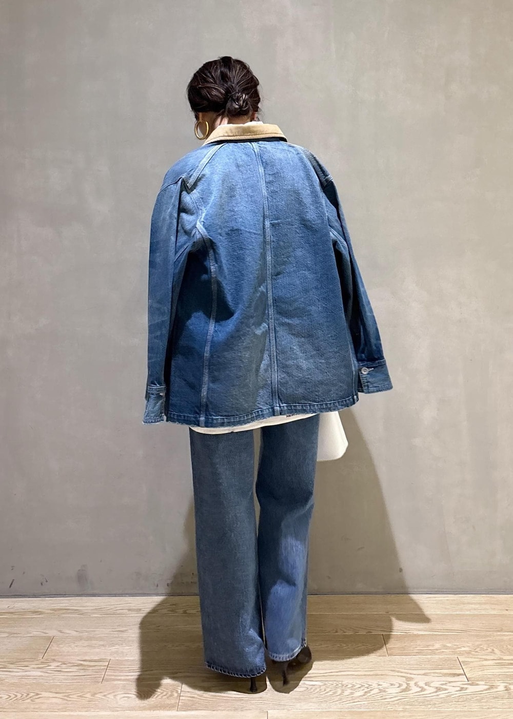 ホワイト系のハンドバッグ、ブルー系のデニムパンツ、ブルー系のデニムジャケットを着用したレディースの冬コーディネートの6枚目の写真