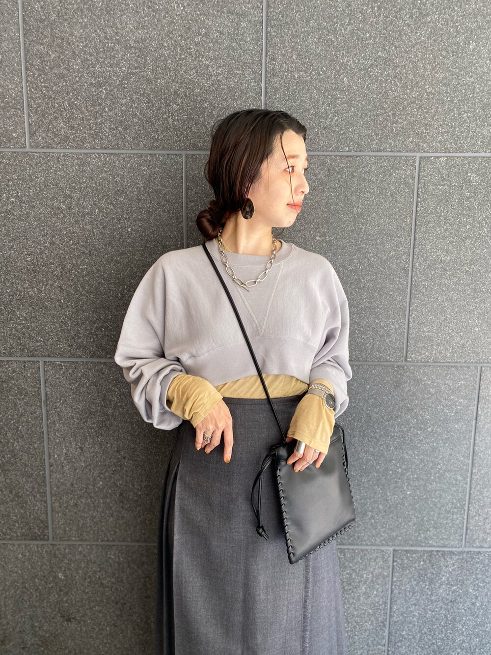 グレー系のスカート、ブラック系のブーツ、ブラック系のショルダーバッグを着用したレディースの春コーディネートの2枚目の写真