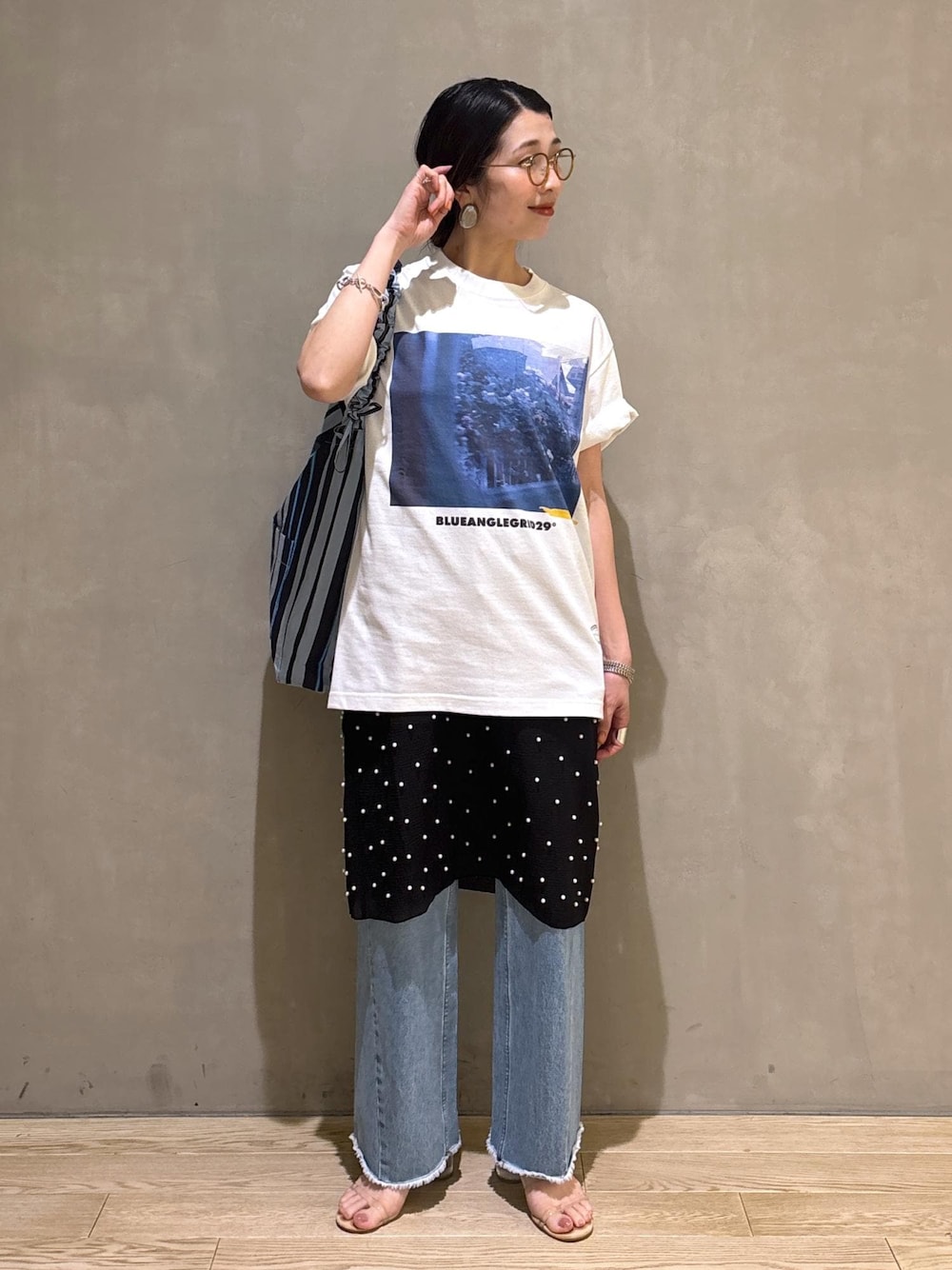 ブルー系のデニムパンツ、ブルー系のショルダーバッグ、ホワイト系のTシャツ/カットソーを着用したレディースの春コーディネートの2枚目の写真