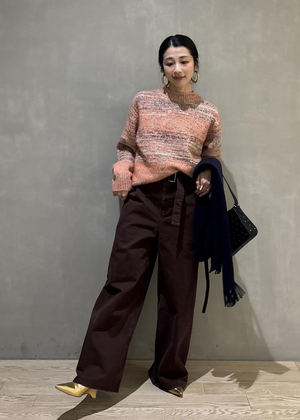 オレンジ系のニット/セーター、ブラック系のショルダーバッグ、ブラウン系のその他パンツを着用したレディースの秋コーディネートの4枚目の写真