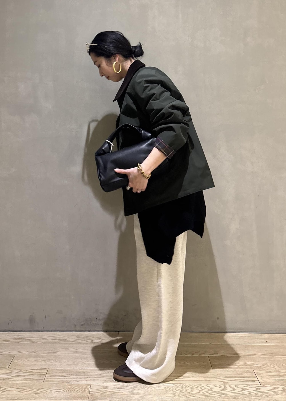 ブラック系のハンドバッグ、グリーン系のその他アウター、ホワイト系のその他パンツを着用したレディースの冬コーディネートの5枚目の写真