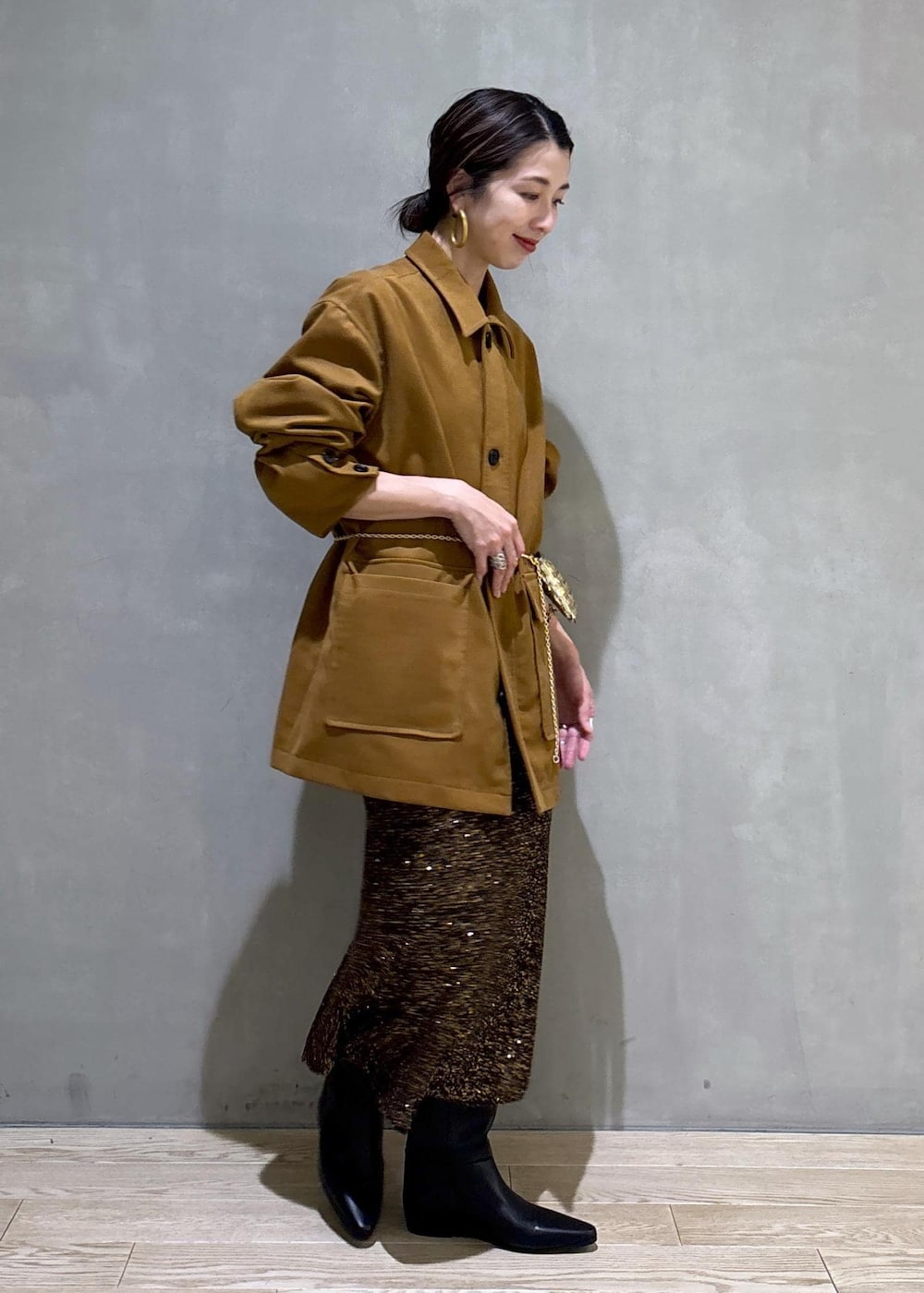 ブラック系のブーツ、ブラック系のスカート、イエロー系のブルゾンを着用したレディースの冬コーディネートの2枚目の写真