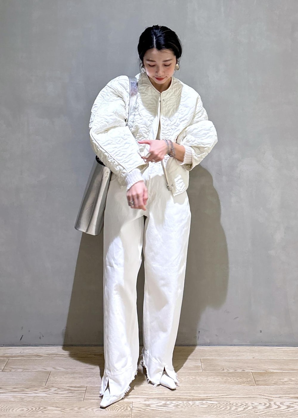 ホワイト系のパンプス、シルバー系のトートバッグ、ホワイト系のデニムパンツを着用したレディースの冬コーディネートの3枚目の写真