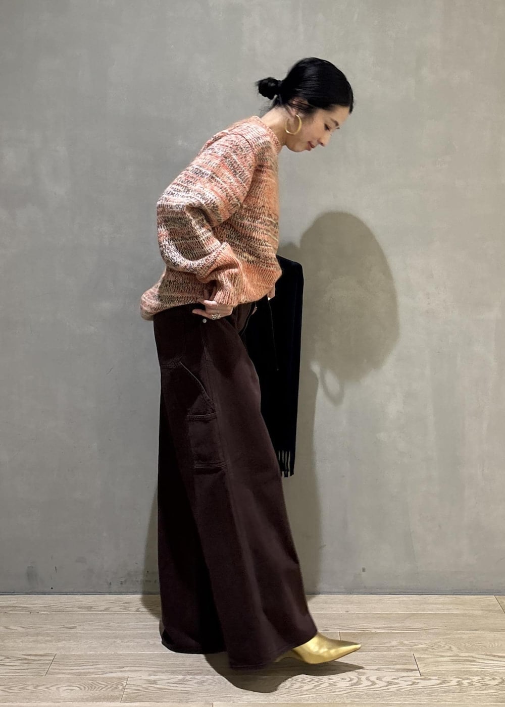 オレンジ系のニット/セーター、ブラック系のショルダーバッグ、ブラウン系のその他パンツを着用したレディースの秋コーディネートの5枚目の写真