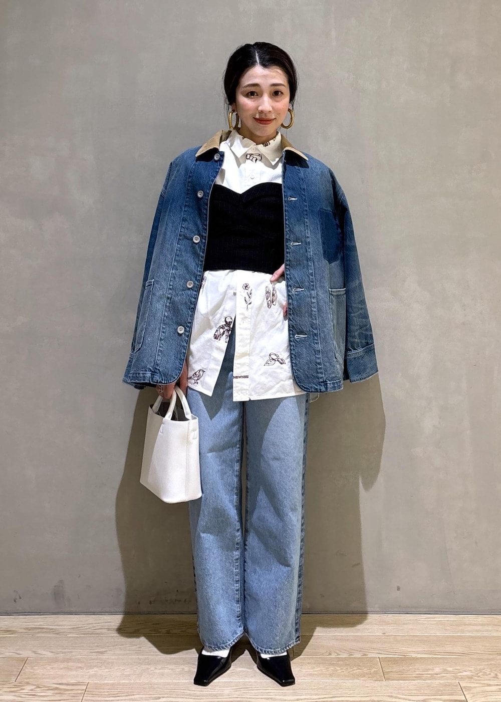 ホワイト系のハンドバッグ、ブルー系のデニムパンツ、ブルー系のデニムジャケットを着用したレディースの冬コーディネートの2枚目の写真