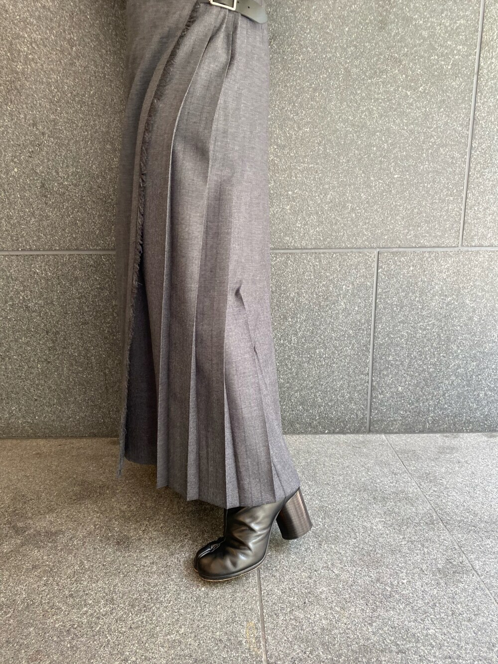 グレー系のスカート、ブラック系のブーツ、ブラック系のショルダーバッグを着用したレディースの春コーディネートの3枚目の写真