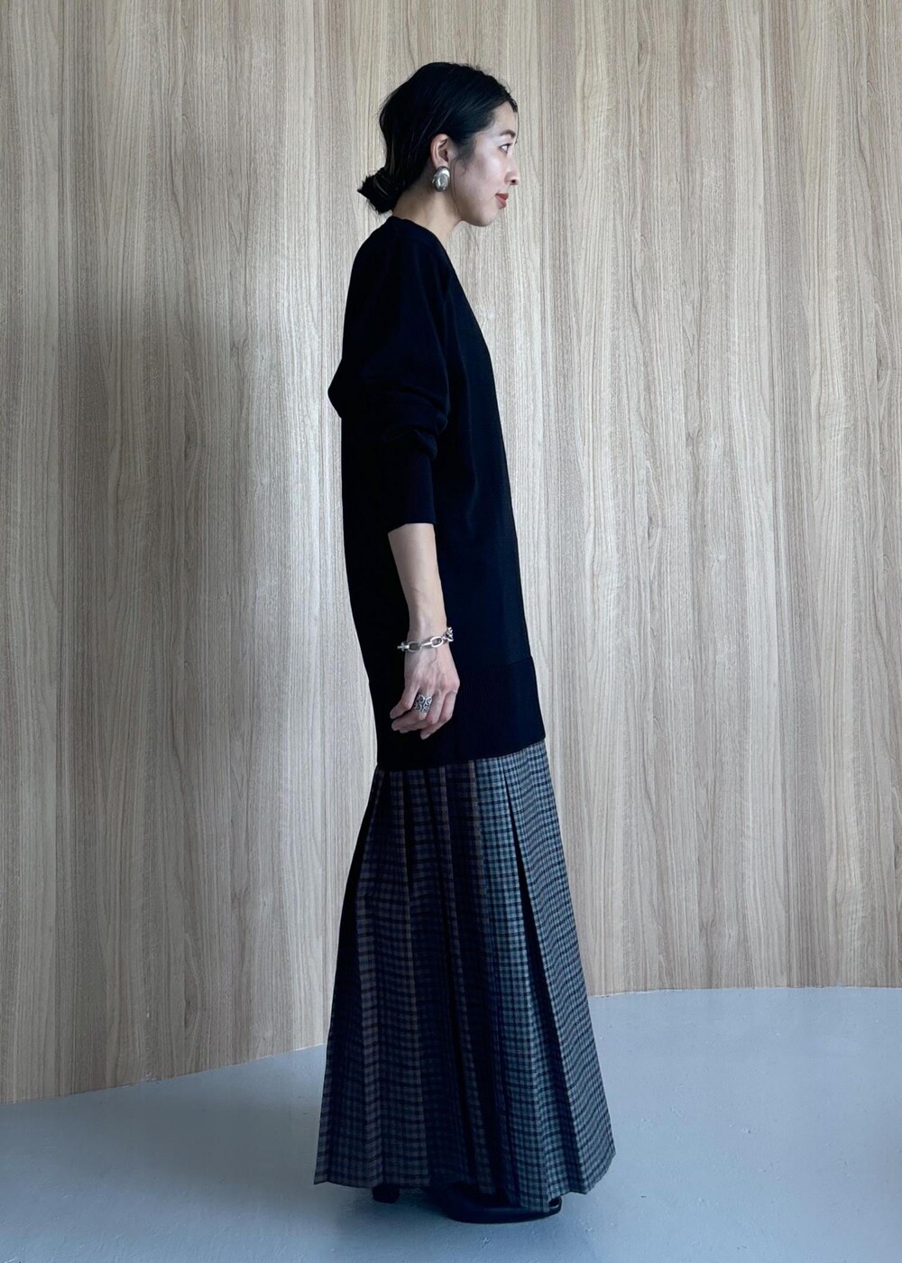 グレー系のスカート、ブラック系のブーツ、ブラック系のニット/セーターを着用したレディースの秋コーディネートの6枚目の写真