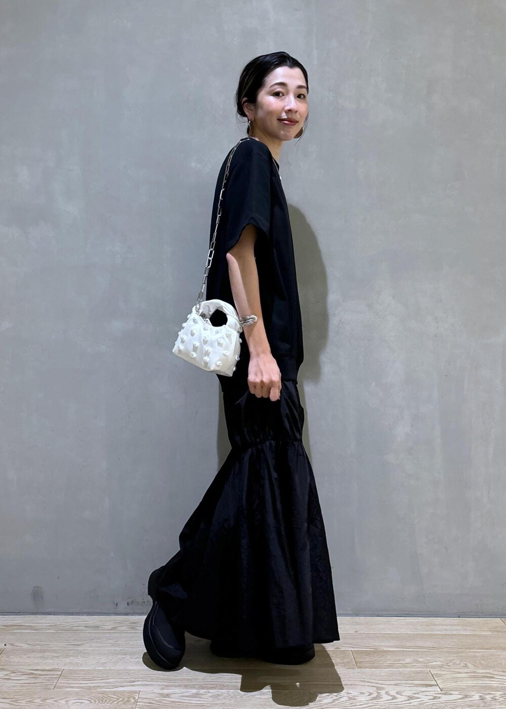 ホワイト系のショルダーバッグ、ブラック系のブーツ、ブラック系のワンピースを着用したレディースの夏コーディネートの4枚目の写真