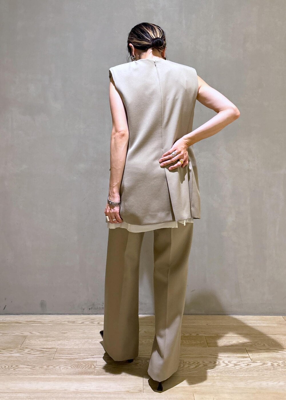 ブラック系のパンプス、ベージュ系のベスト、ベージュ系のスラックスを着用したレディースの夏コーディネートの4枚目の写真