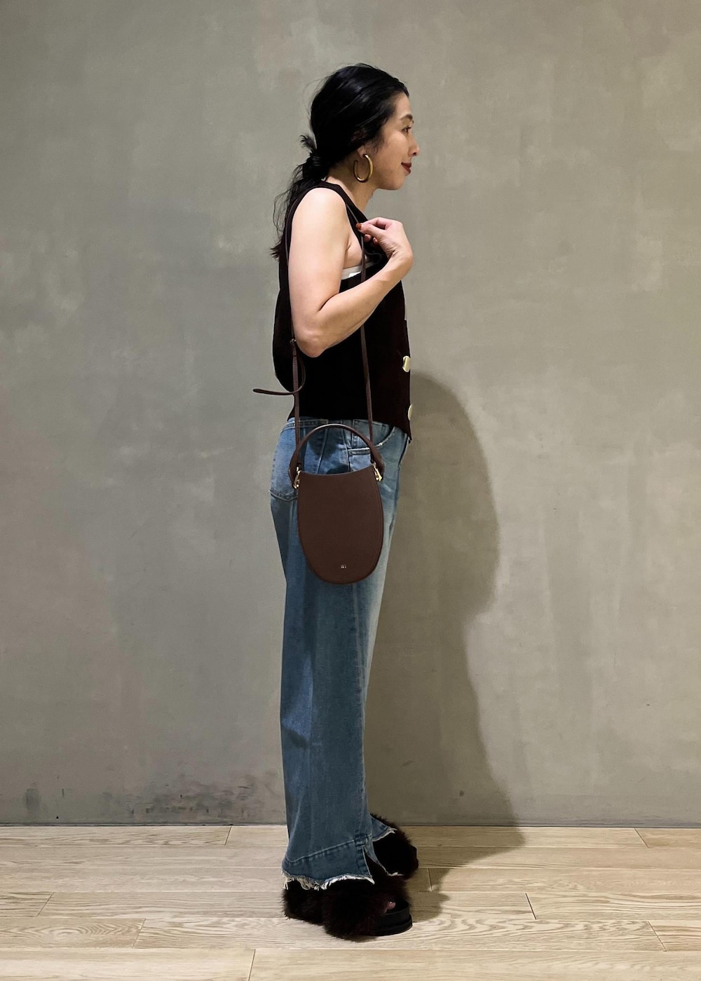 ブルー系のデニムパンツ、ブラウン系のサンダル、ブラウン系のベストを着用したレディースの夏コーディネートの4枚目の写真