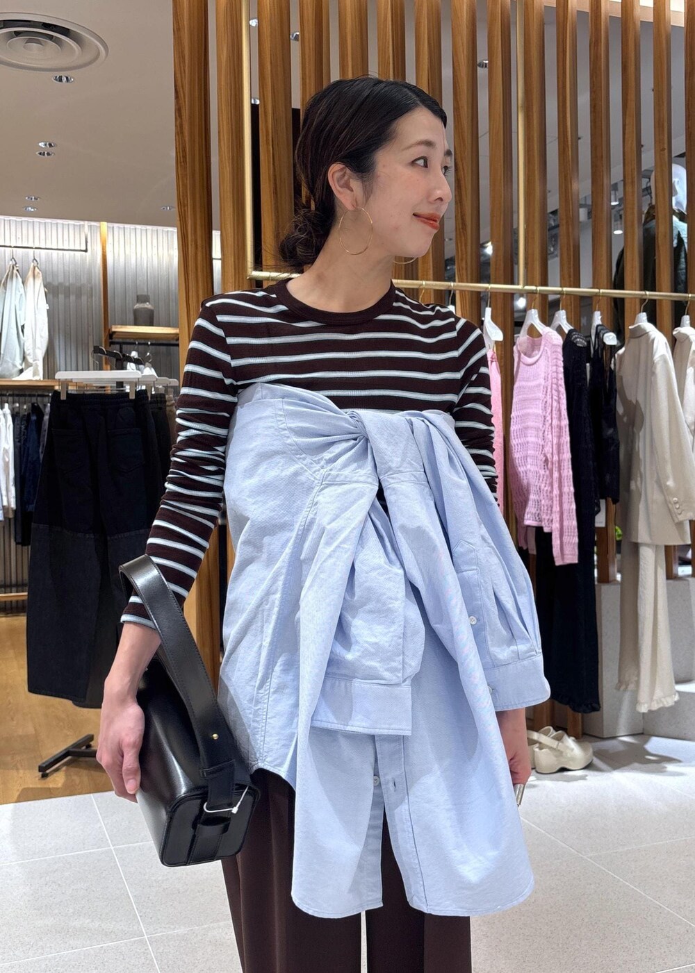 ブラック系のハンドバッグ、ブルー系のシャツ/ブラウス、ブラウン系のTシャツ/カットソーを着用したレディースの春コーディネートの8枚目の写真