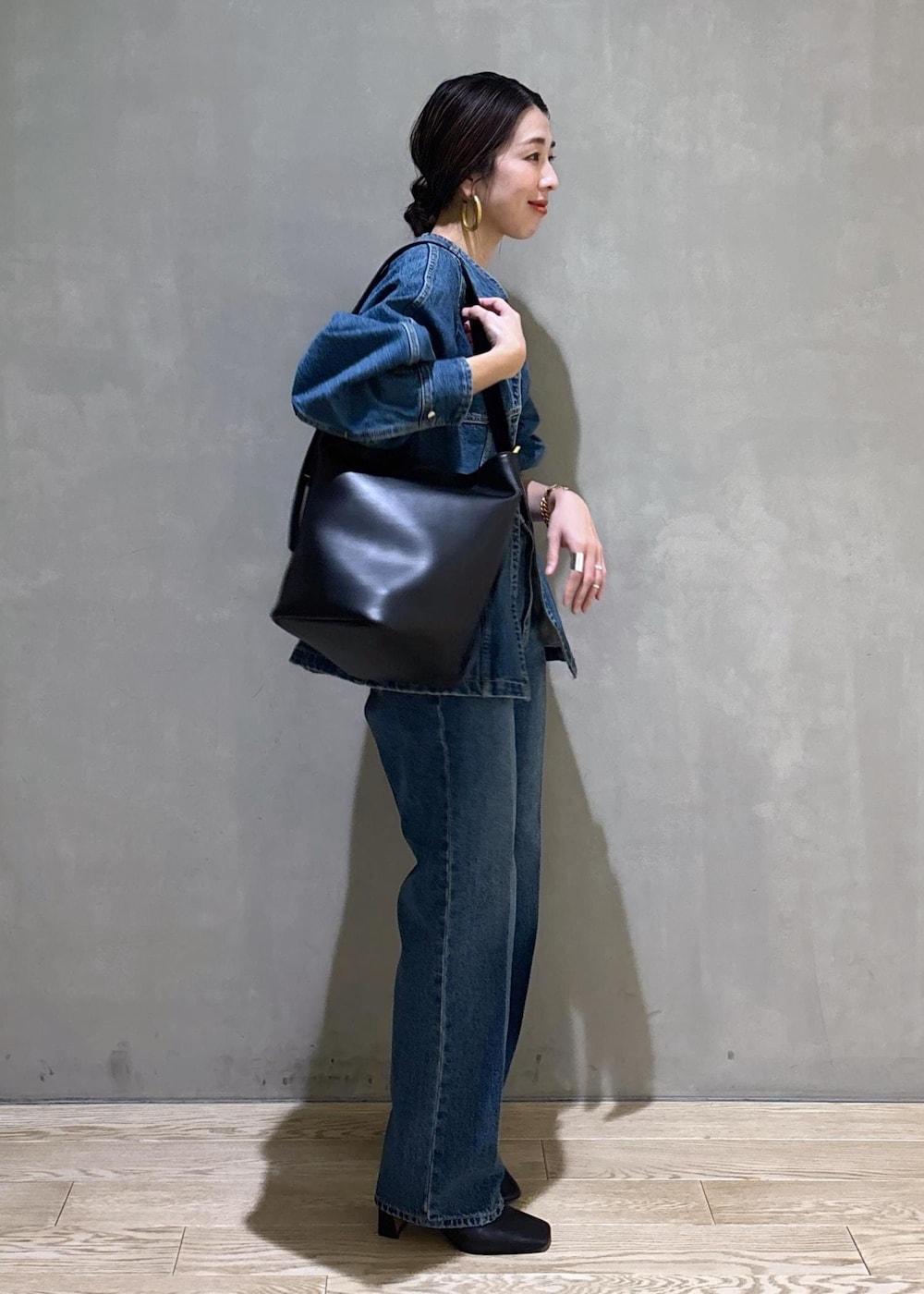 ブルー系のシャツ/ブラウス、ブルー系のデニムパンツ、ブラック系のショルダーバッグを着用したレディースの冬コーディネートの3枚目の写真