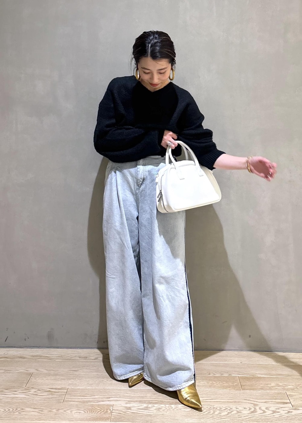 ブラック系のニット/セーター、ホワイト系のボストンバッグ、ブルー系のその他パンツを着用したレディースの冬コーディネートの6枚目の写真