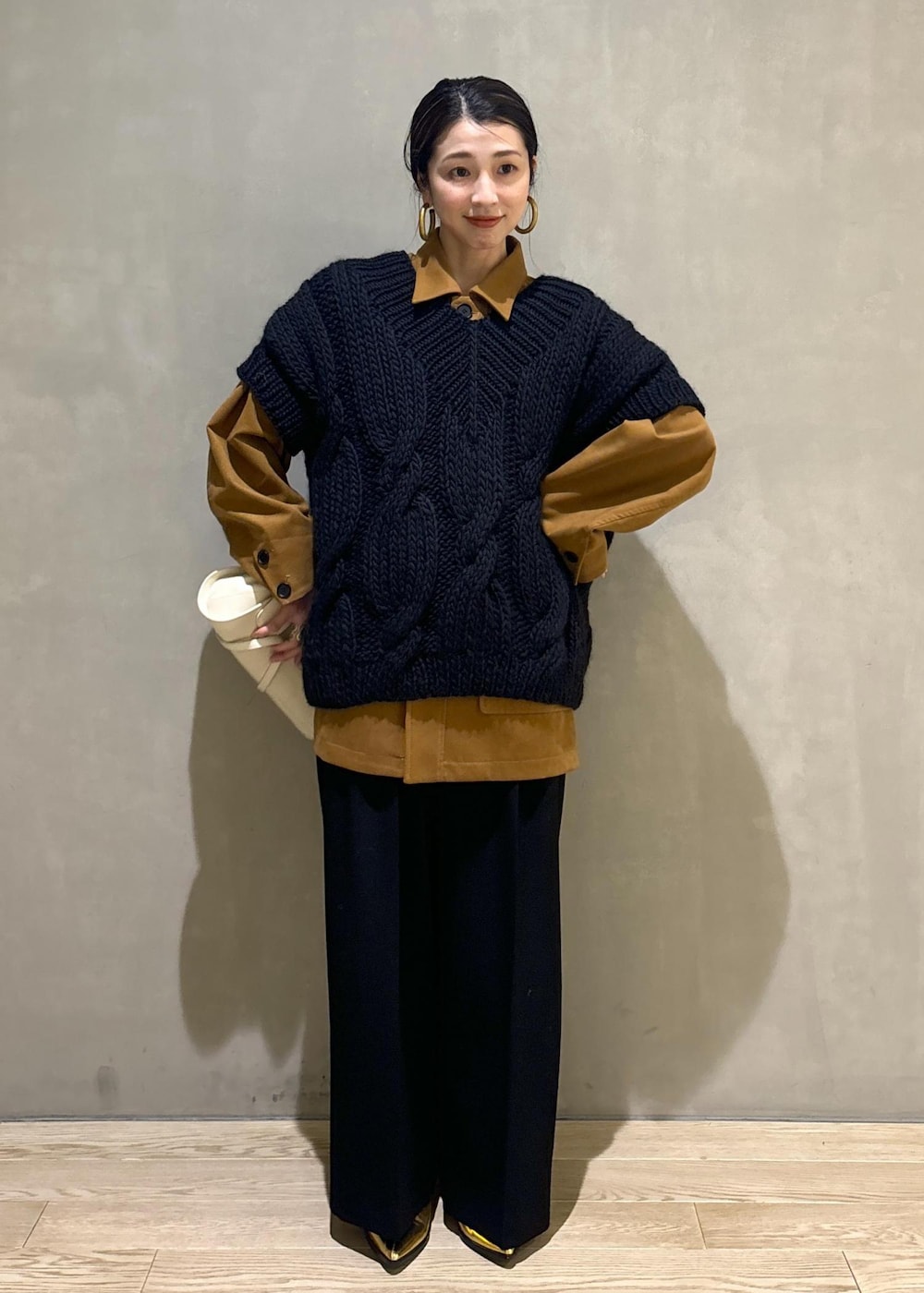 ブラック系のニット/セーター、ゴールド系のブーツ、イエロー系のブルゾンを着用したレディースの秋コーディネートの2枚目の写真