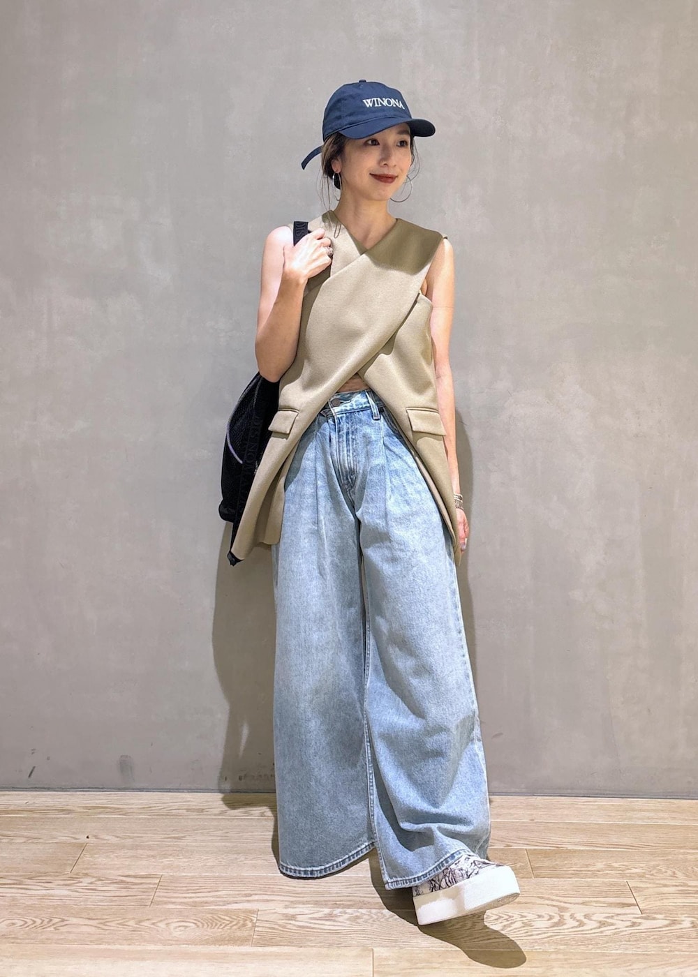 ベージュ系のベスト、ブラック系のスニーカー、ブラック系のショルダーバッグを着用したレディースの夏コーディネートの2枚目の写真