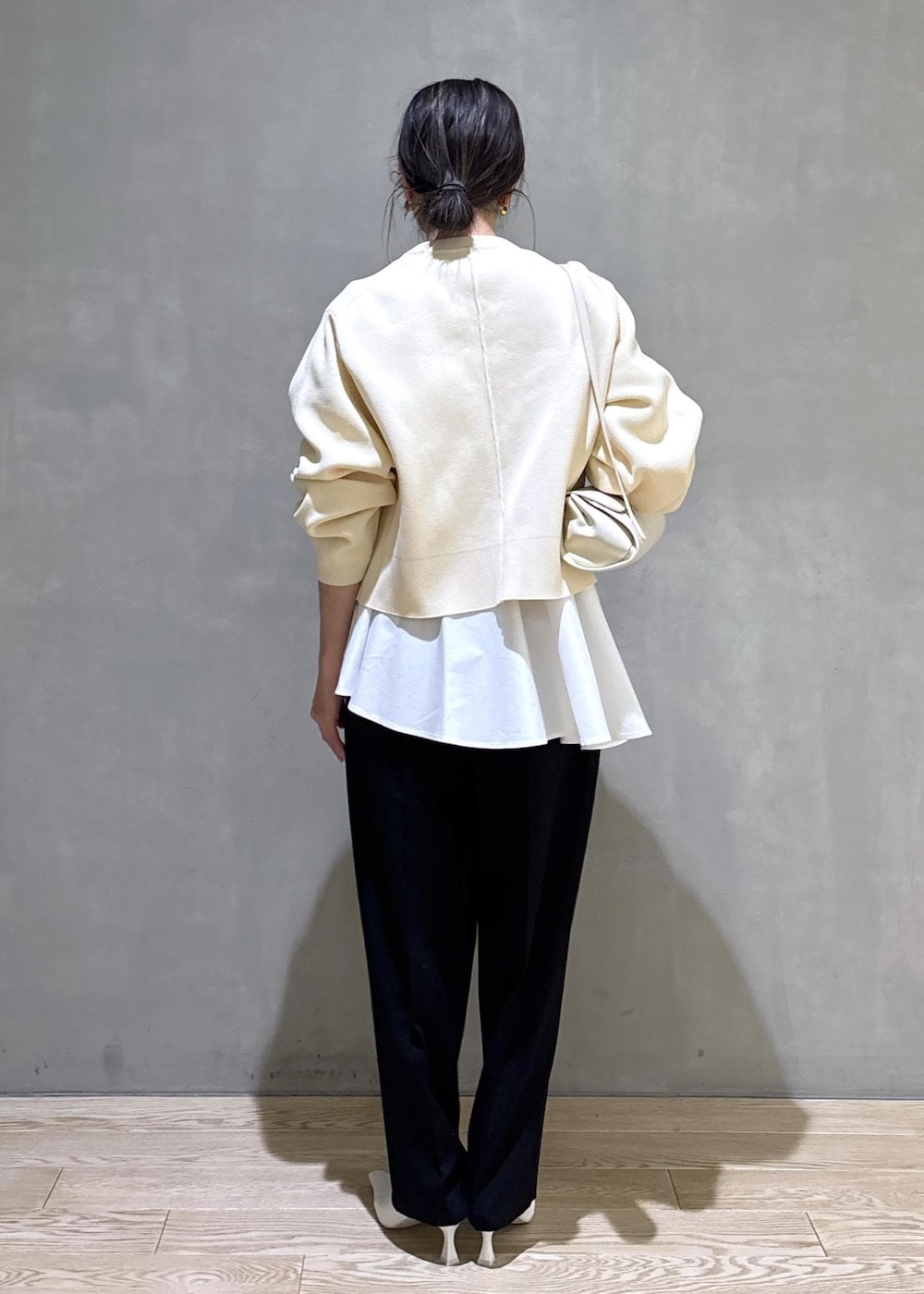 ホワイト系のパンプス、ブラック系のスラックス、ホワイト系のショルダーバッグを着用したレディースの冬コーディネートの4枚目の写真