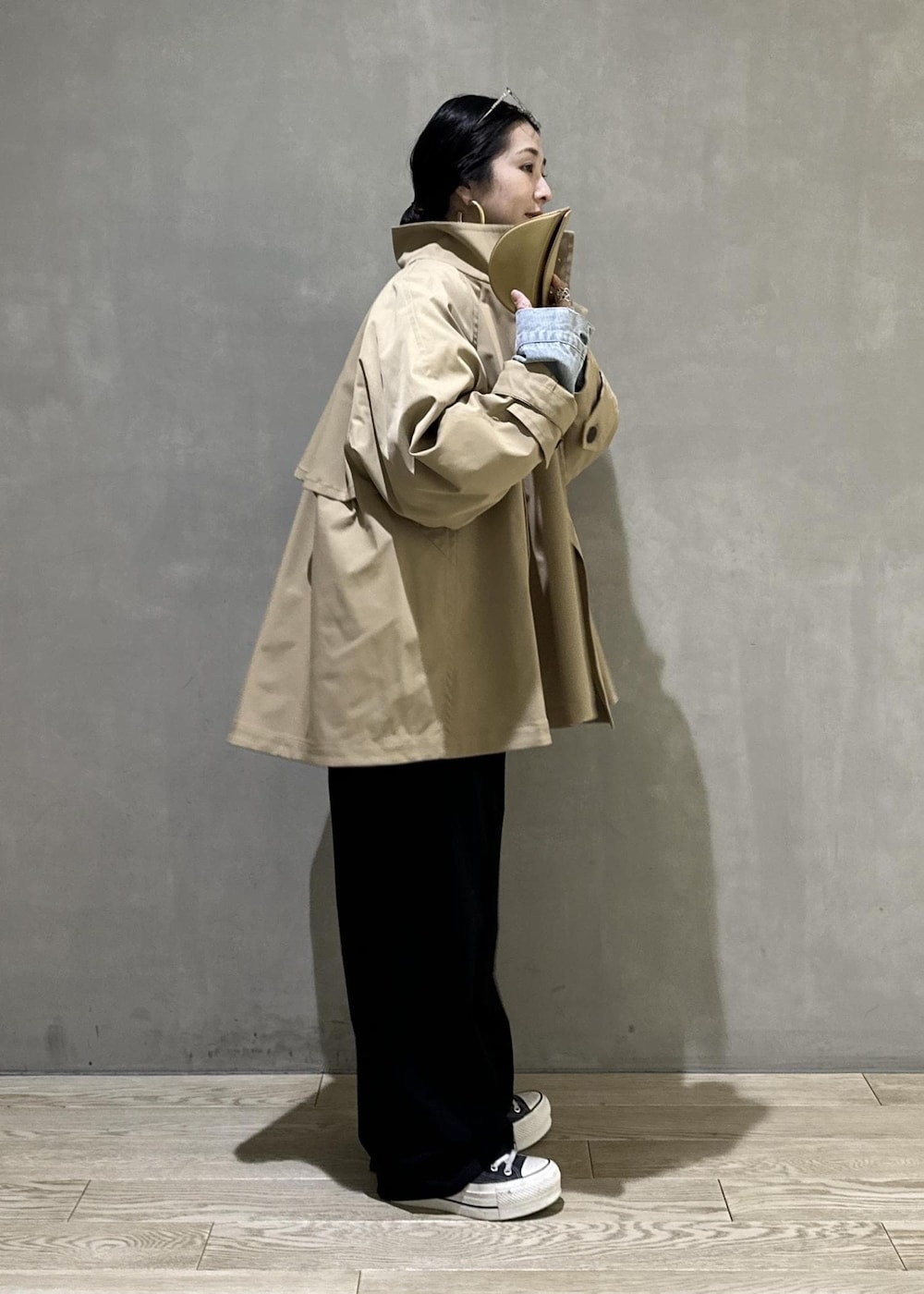 ベージュ系のトレンチコート、ブラック系のスラックス、イエロー系のキーホルダーを着用したレディースの冬コーディネートの4枚目の写真