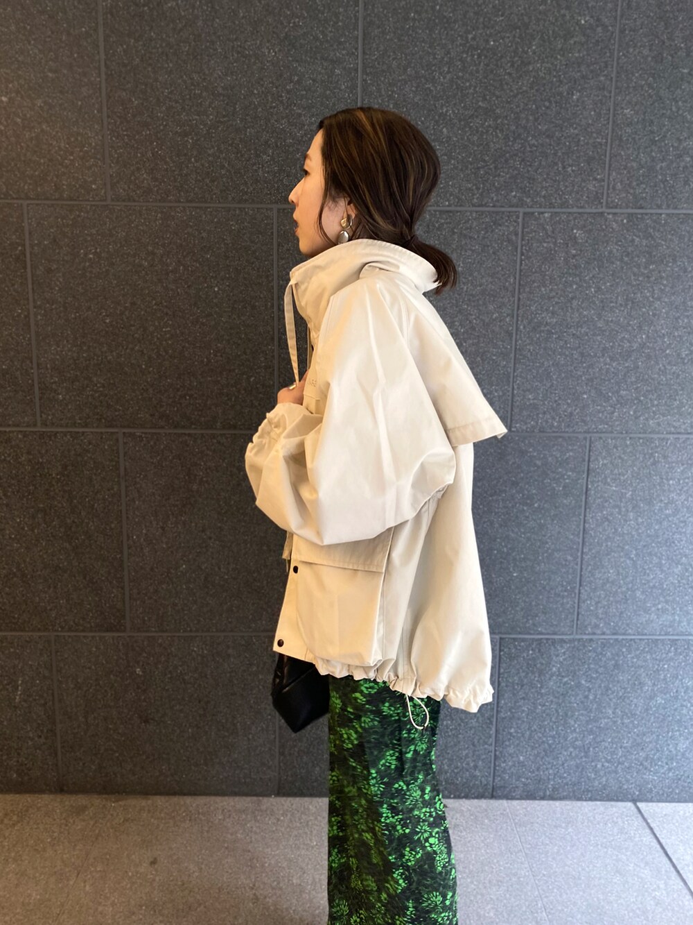 ブラック系のカーゴパンツ、ブラック系のクラッチバッグ、ホワイト系のブルゾンを着用したレディースの春コーディネートの3枚目の写真