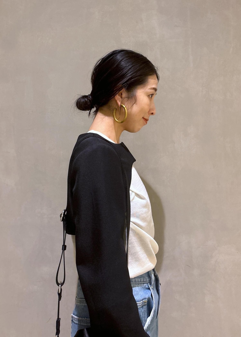 ブルー系のデニムパンツ、ゴールド系のパンプス、ブラック系のノーカラージャケットを着用したレディースの秋コーディネートの8枚目の写真