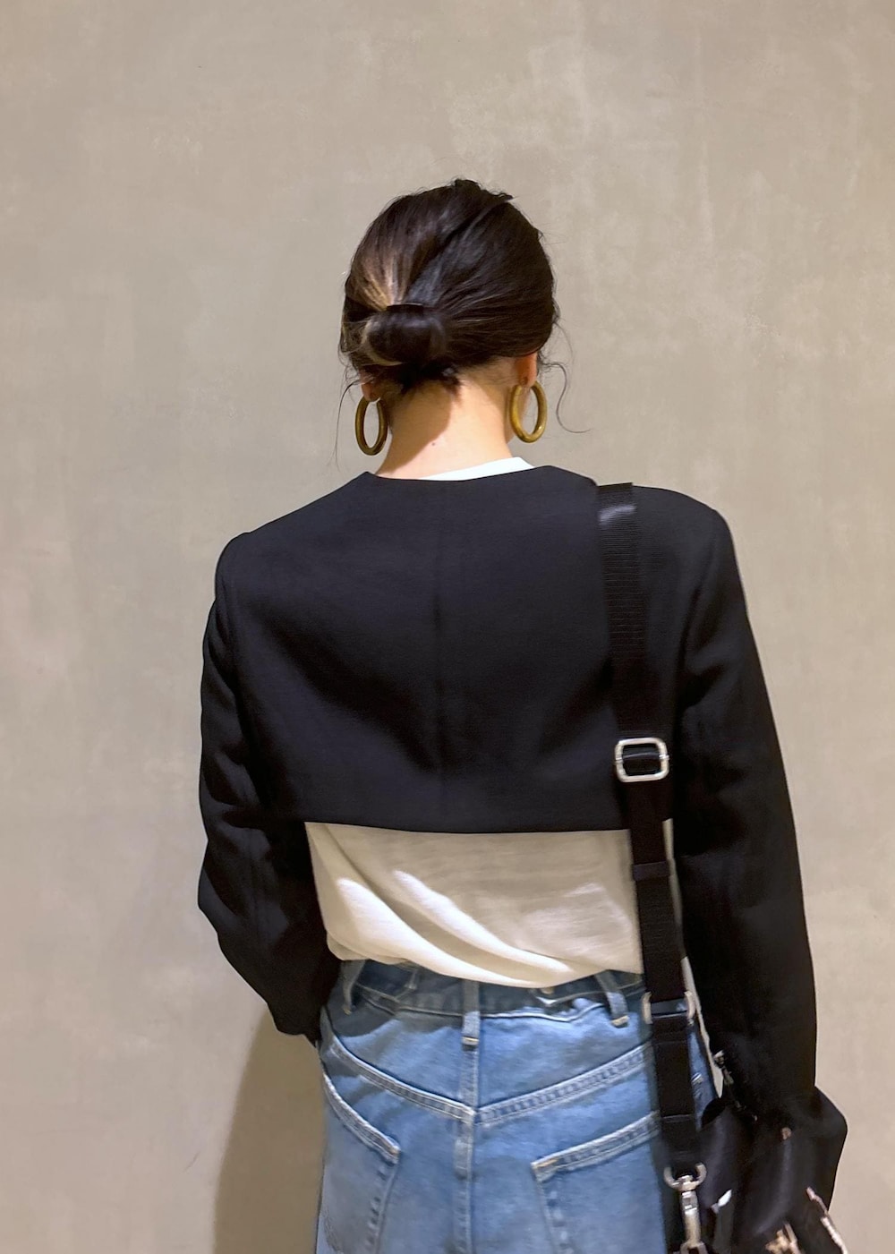 ブルー系のデニムパンツ、ゴールド系のパンプス、ブラック系のノーカラージャケットを着用したレディースの秋コーディネートの9枚目の写真