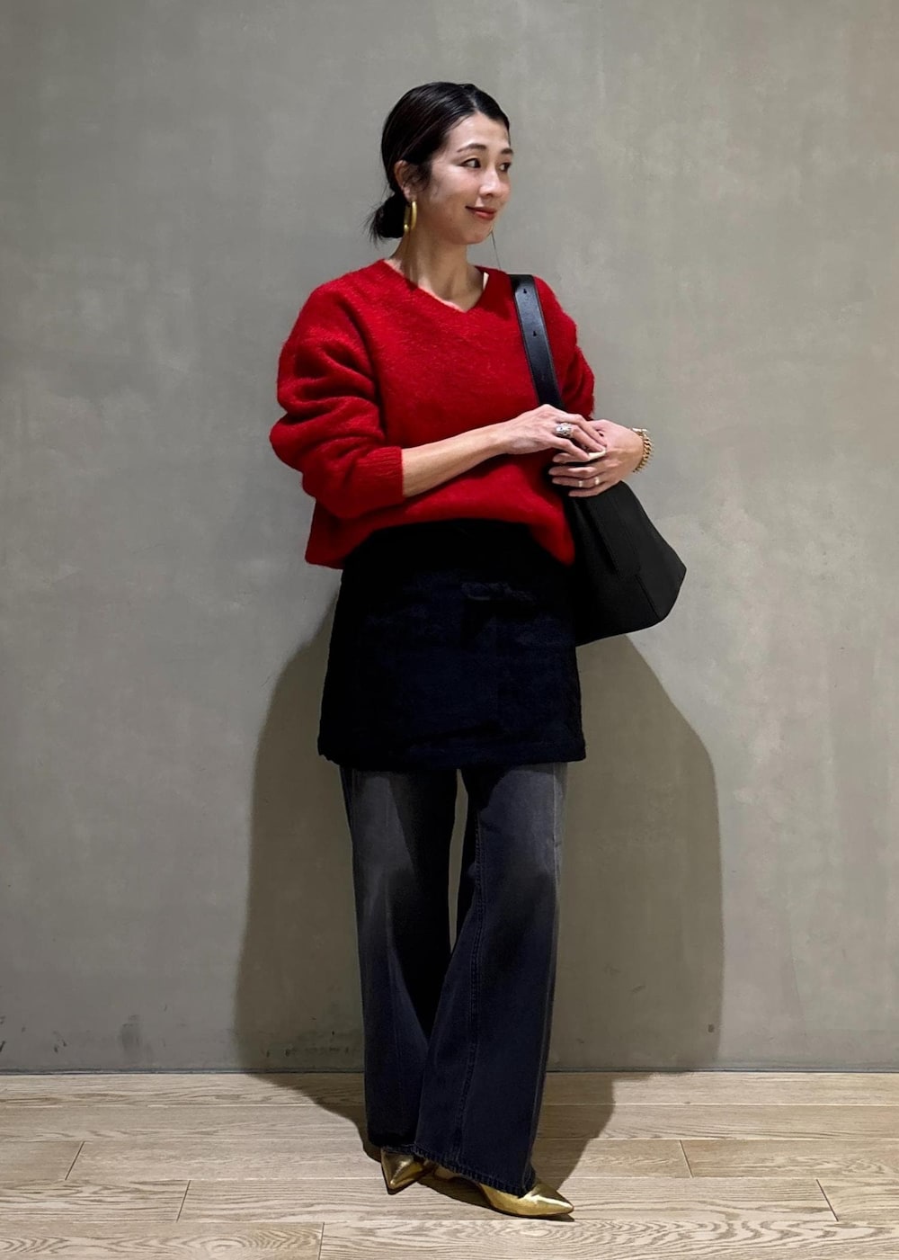 レッド系のニット/セーター、ブラック系のスカート、ブラック系のデニムパンツを着用したレディースの冬コーディネートの4枚目の写真