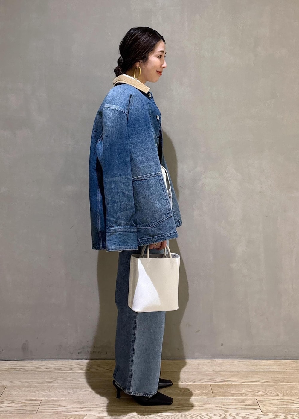 ホワイト系のハンドバッグ、ブルー系のデニムパンツ、ブルー系のデニムジャケットを着用したレディースの冬コーディネートの5枚目の写真