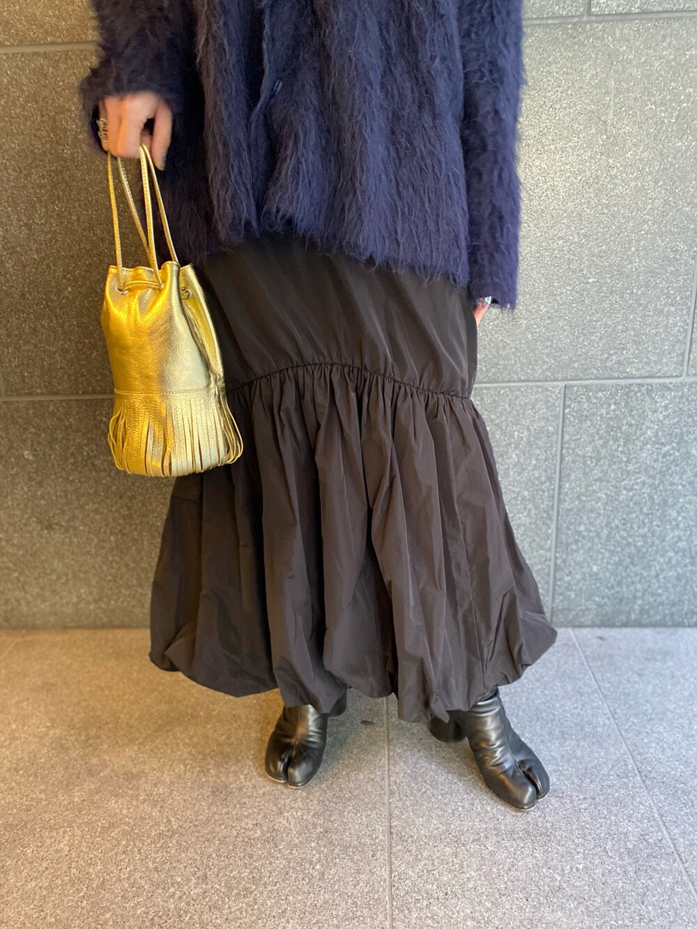 ブルー系のカーディガン/ボレロ、ブラック系のスカート、ゴールド系のバッグを着用したレディースの春コーディネートの3枚目の写真