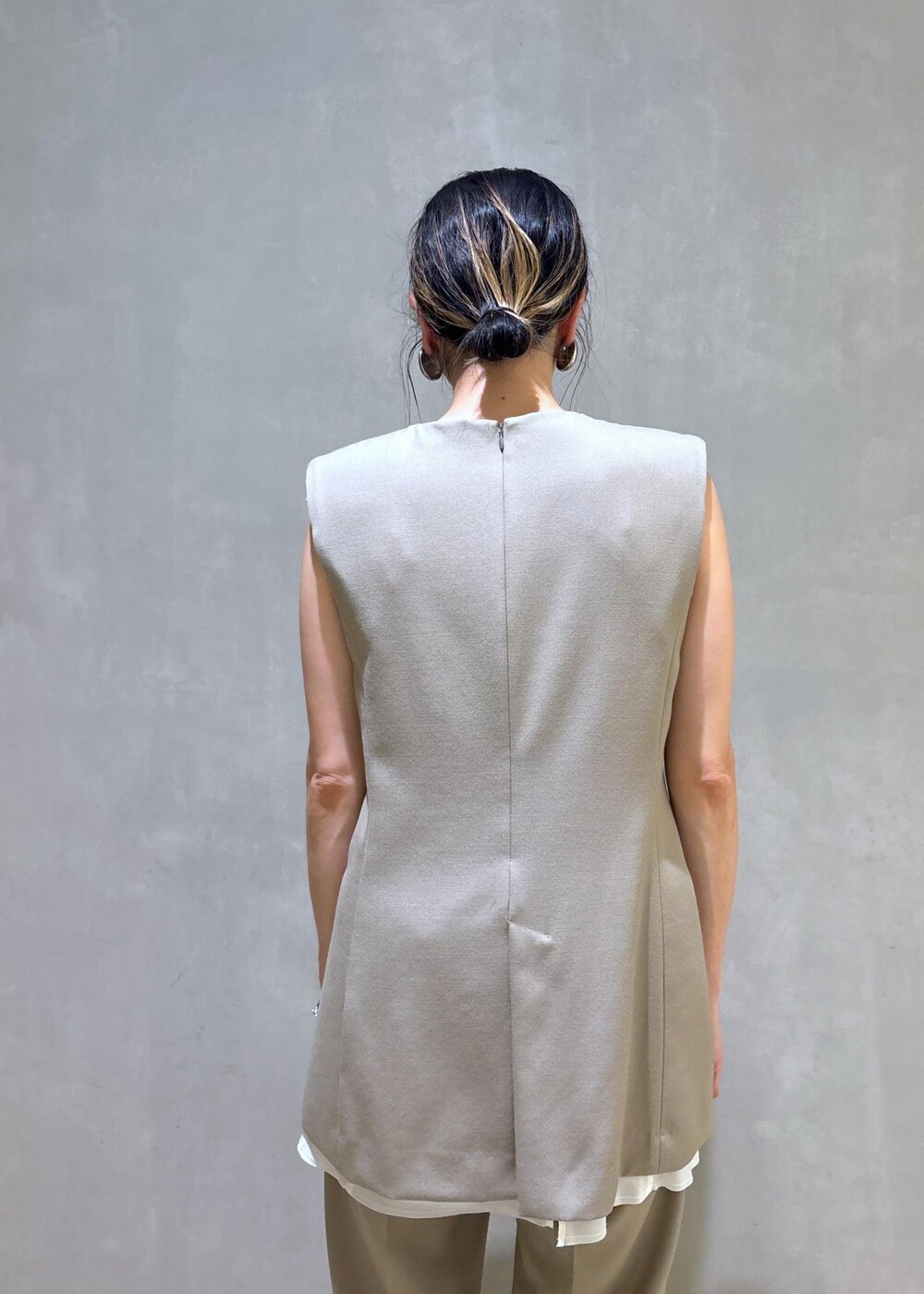 ブラック系のパンプス、ベージュ系のベスト、ベージュ系のスラックスを着用したレディースの夏コーディネートの10枚目の写真