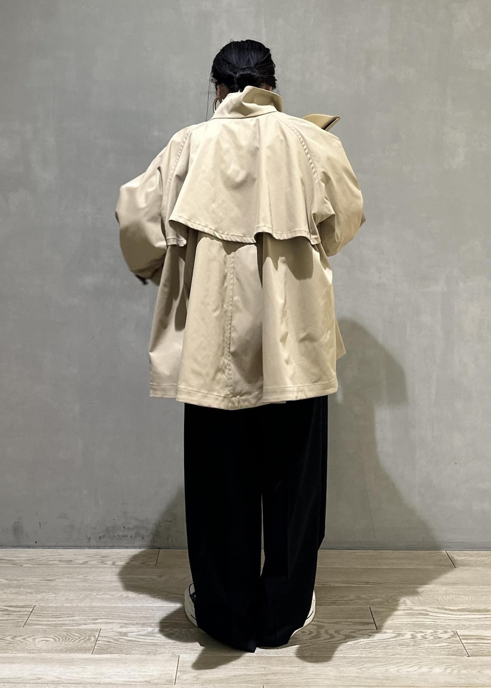 ベージュ系のトレンチコート、ブラック系のスラックス、イエロー系のキーホルダーを着用したレディースの冬コーディネートの5枚目の写真