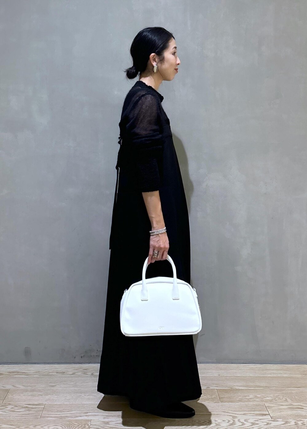 ホワイト系のボストンバッグ、ブラック系のワンピース、ブラック系のブーツを着用したレディースの秋コーディネートの4枚目の写真