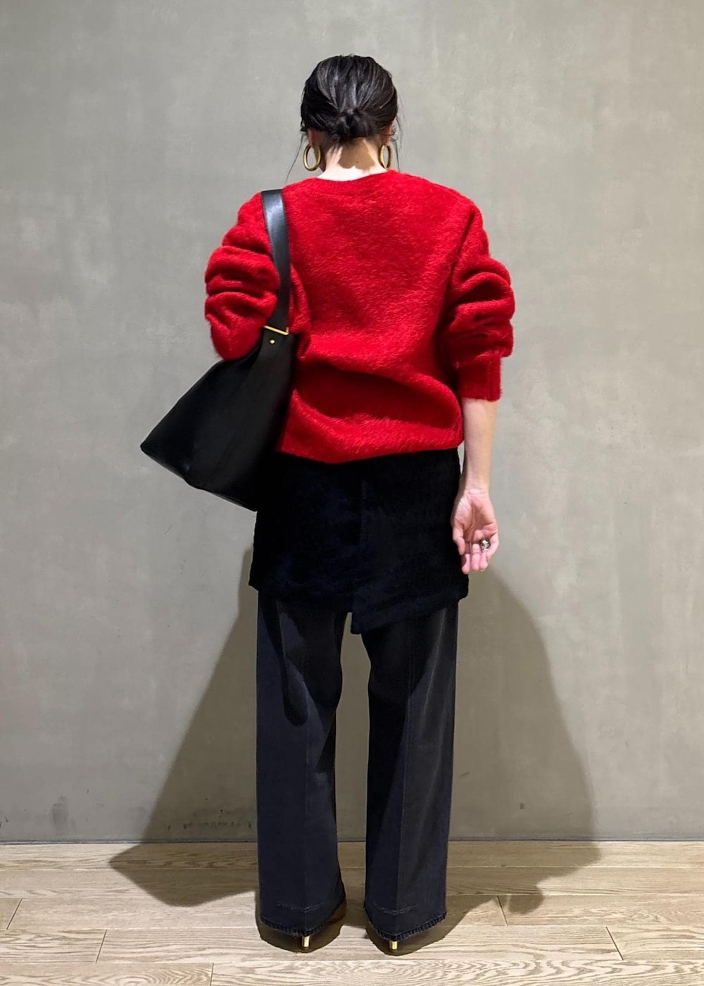 レッド系のニット/セーター、ブラック系のスカート、ブラック系のデニムパンツを着用したレディースの冬コーディネートの6枚目の写真