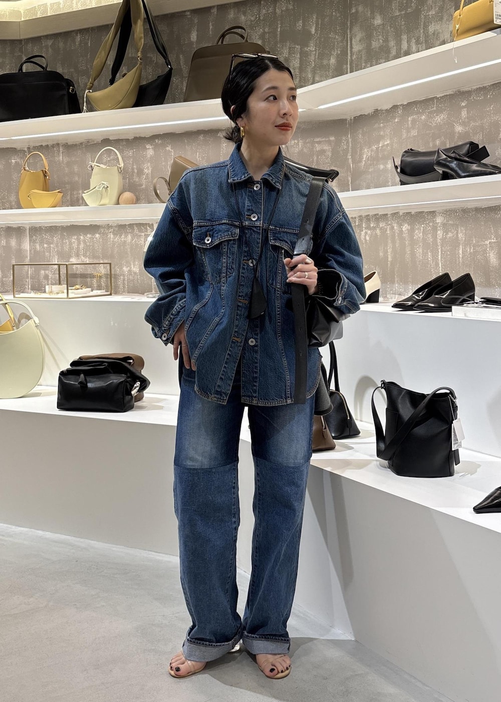 ブルー系のデニムジャケット、ブラック系のショルダーバッグ、ブルー系のデニムパンツを着用したレディースの春コーディネートの3枚目の写真