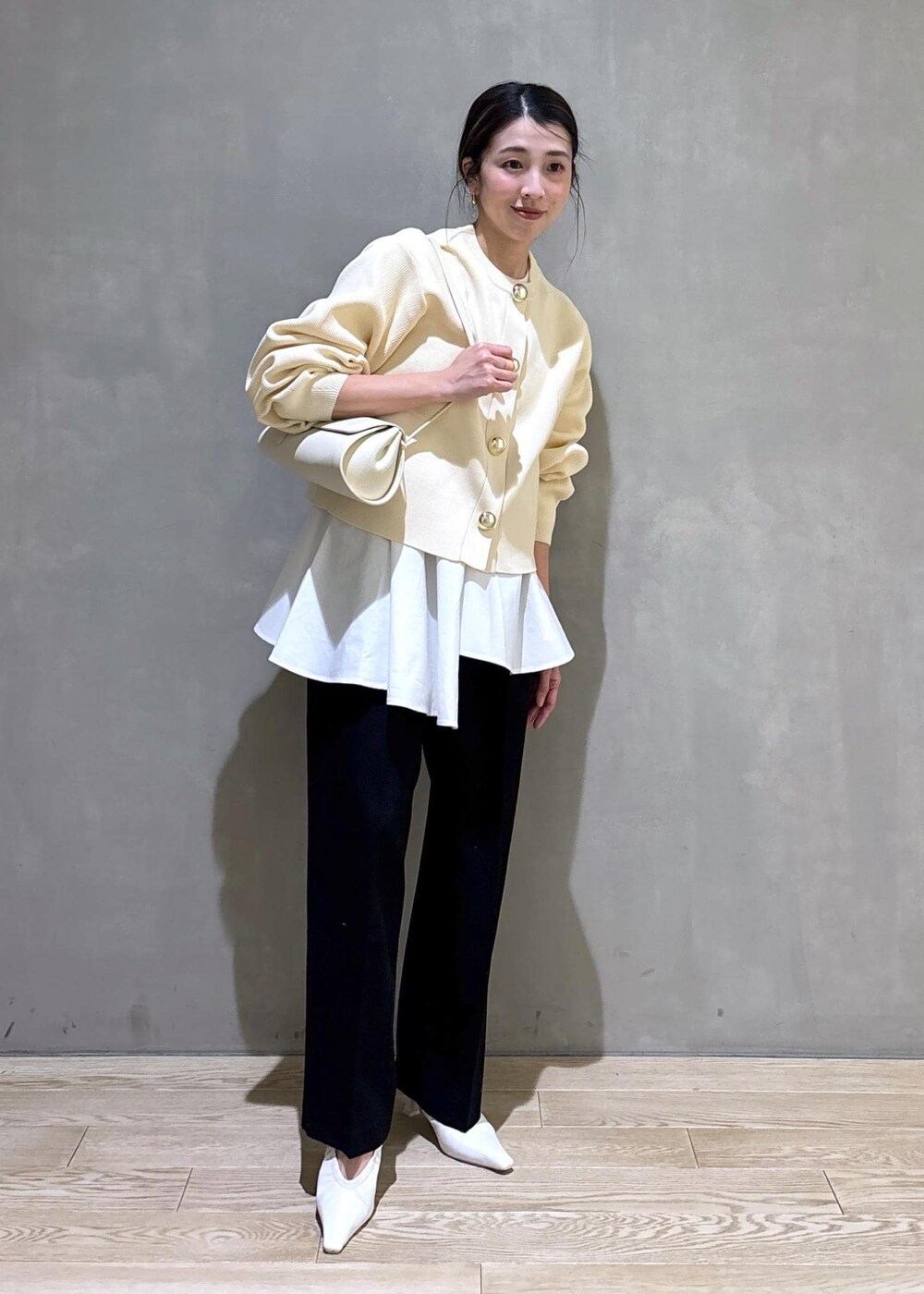 ホワイト系のパンプス、ブラック系のスラックス、ホワイト系のショルダーバッグを着用したレディースの冬コーディネートの7枚目の写真