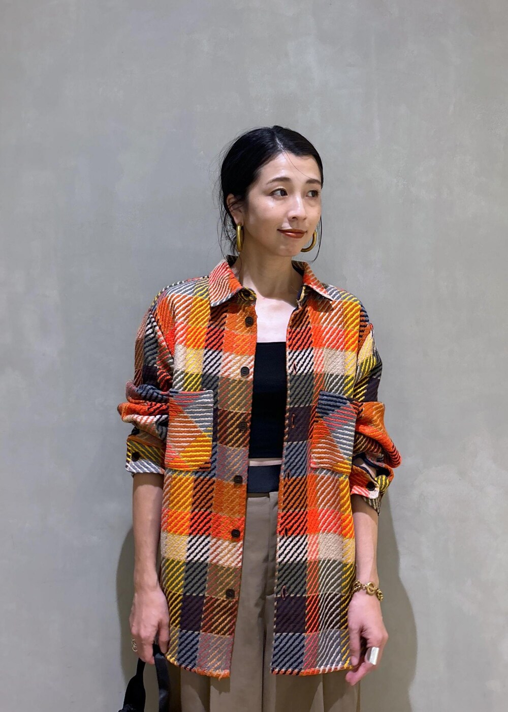 ブラック系のハンドバッグ、グリーン系のスラックスを着用したレディースの秋コーディネートの6枚目の写真