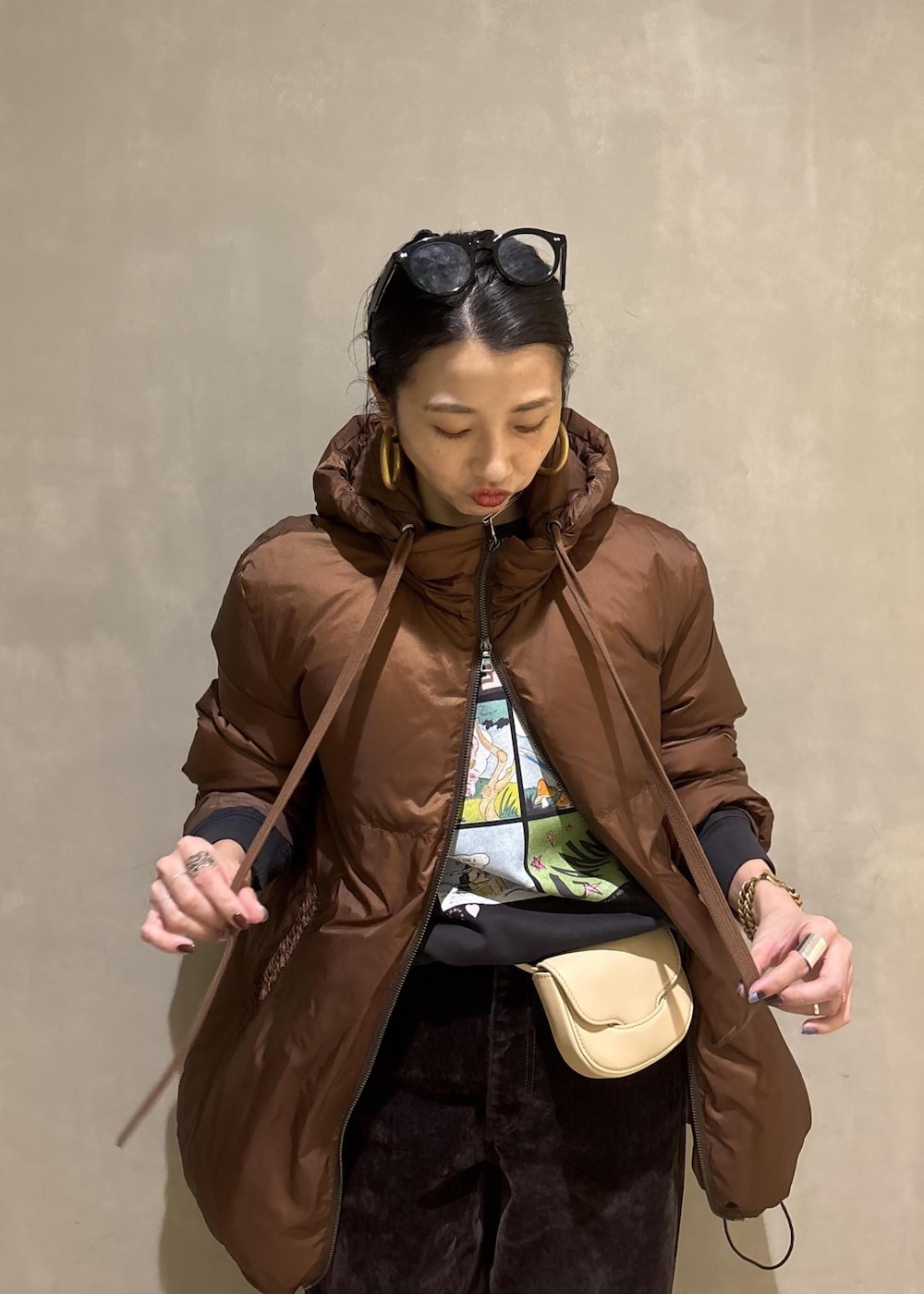 グレー系のスウェット、ブラウン系のダウンジャケット/コート、ブラウン系のデニムパンツを着用したレディースの秋コーディネートの9枚目の写真