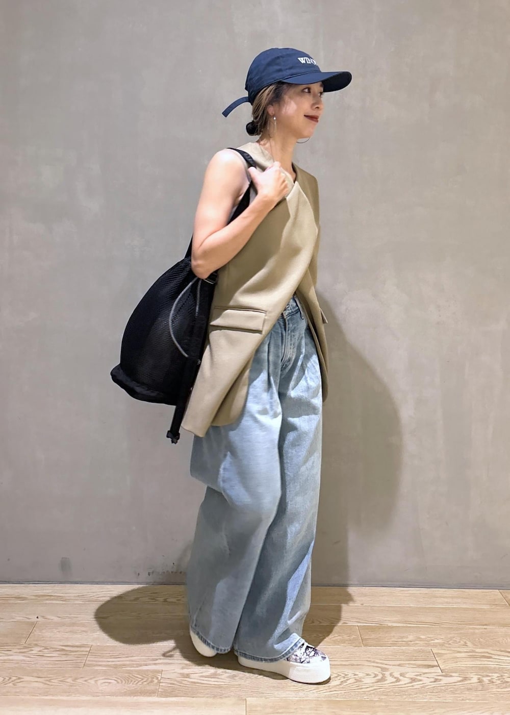 ベージュ系のベスト、ブラック系のスニーカー、ブラック系のショルダーバッグを着用したレディースの夏コーディネートの4枚目の写真