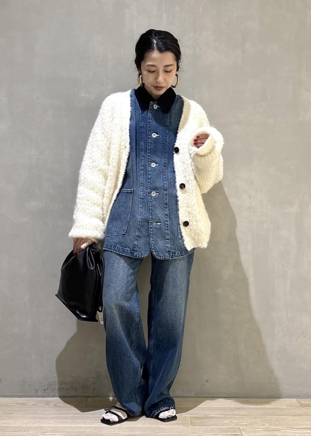 ブラック系のショルダーバッグ、ブルー系のデニムパンツ、ブルー系のカバーオールを着用したレディースの秋コーディネートの2枚目の写真