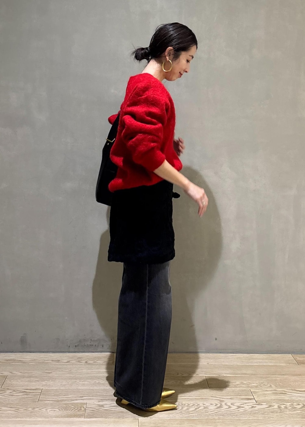 レッド系のニット/セーター、ブラック系のスカート、ブラック系のデニムパンツを着用したレディースの冬コーディネートの5枚目の写真