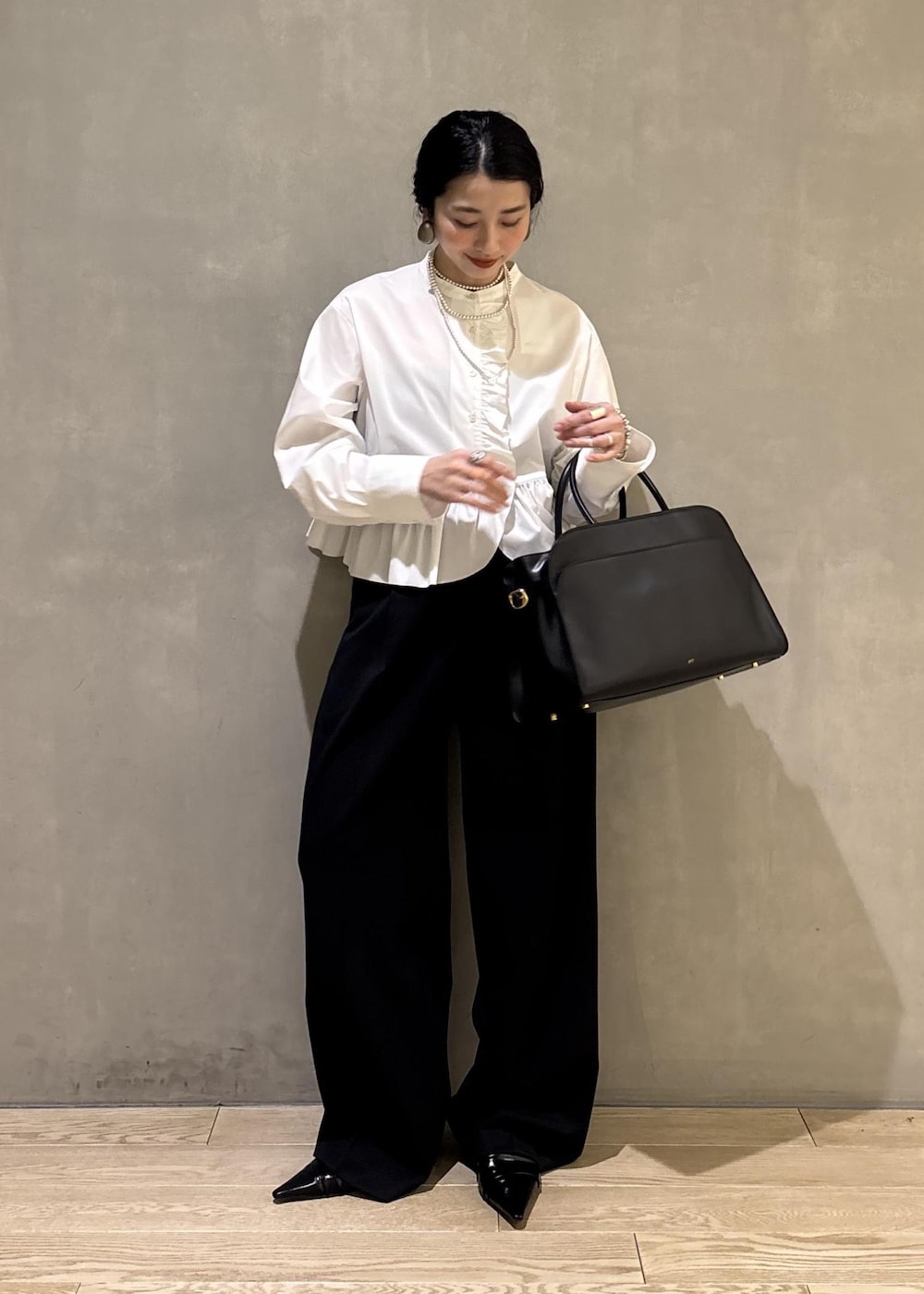 ホワイト系のシャツ/ブラウス、ブラック系のスラックス、ブラック系のトートバッグを着用したレディースの冬コーディネートの5枚目の写真