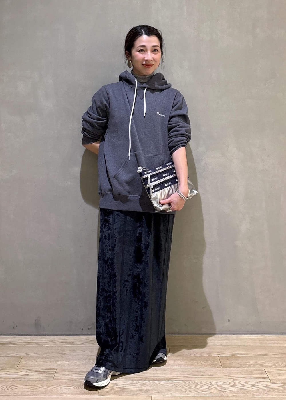 グレー系のスニーカー、ブラック系のスカート、グレー系のパーカーを着用したレディースの冬コーディネートの2枚目の写真