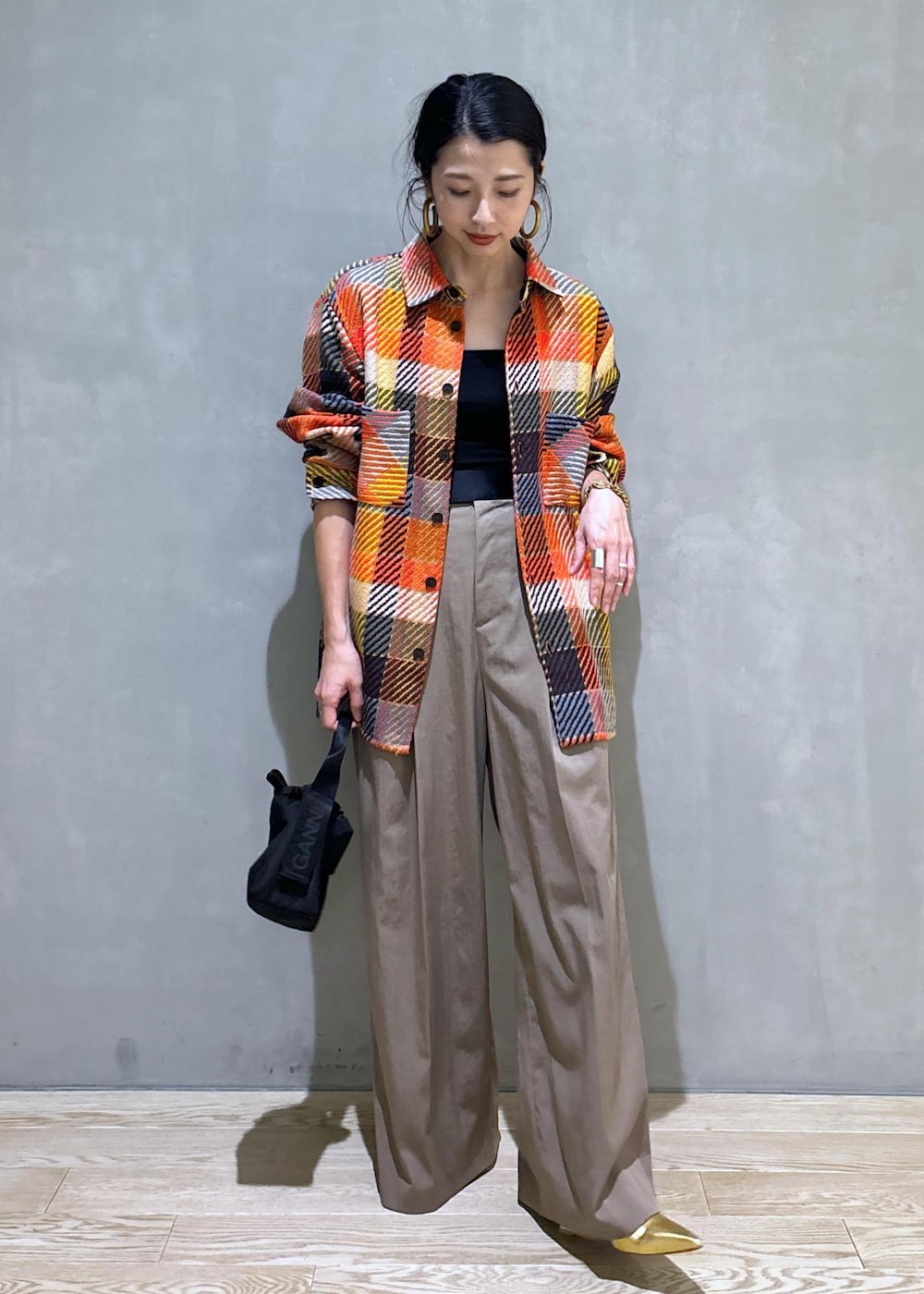 ブラック系のハンドバッグ、グリーン系のスラックスを着用したレディースの秋コーディネートの3枚目の写真