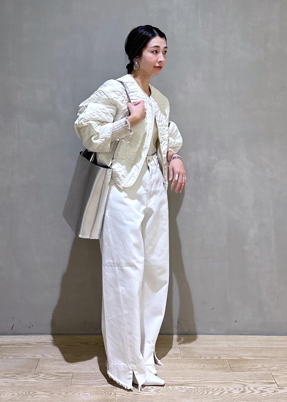 ホワイト系のパンプス、シルバー系のトートバッグ、ホワイト系のデニムパンツを着用したレディースの冬コーディネートの4枚目の写真