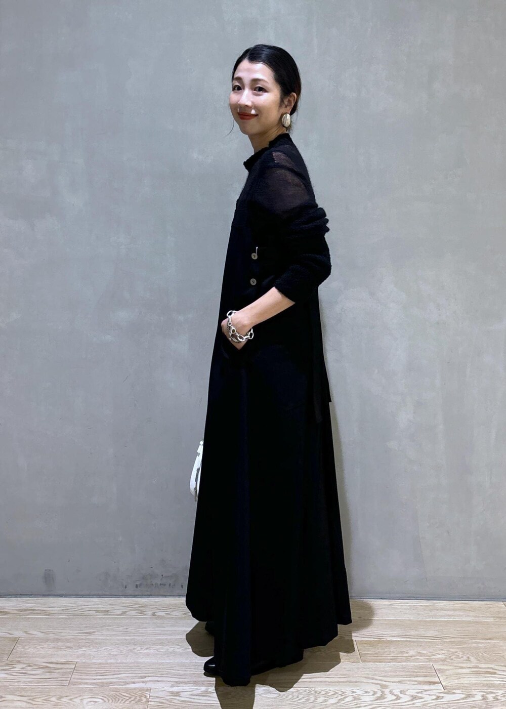 ホワイト系のボストンバッグ、ブラック系のワンピース、ブラック系のブーツを着用したレディースの秋コーディネートの7枚目の写真