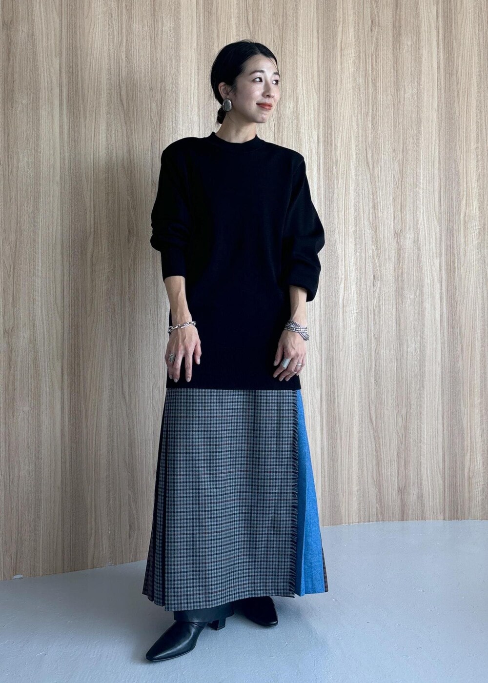 グレー系のスカート、ブラック系のブーツ、ブラック系のニット/セーターを着用したレディースの秋コーディネートの2枚目の写真