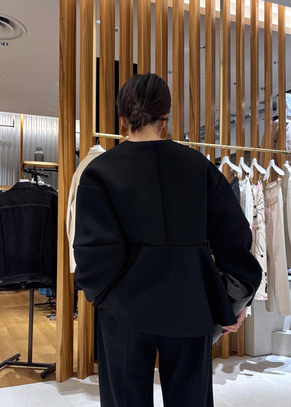 ブラック系のショルダーバッグ、ホワイト系のパンプス、ブラック系のスラックスを着用したレディースの冬コーディネートの9枚目の写真