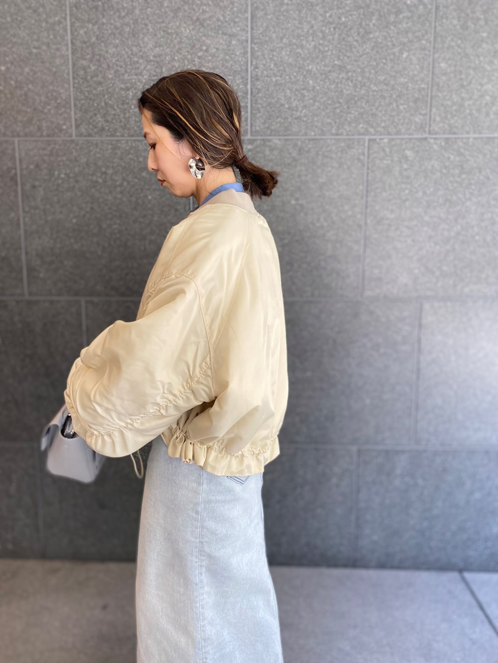 ブルー系のデニムスカート、ホワイト系のパンプス、グレー系のショルダーバッグを着用したレディースの春コーディネートの3枚目の写真